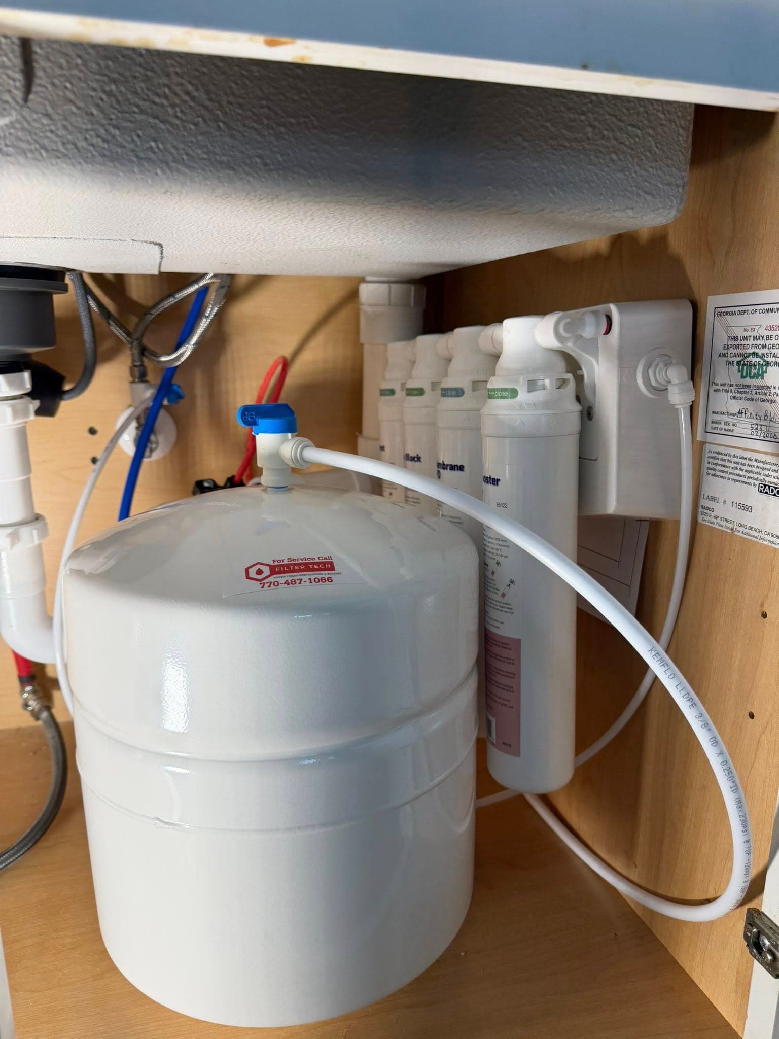 A Filter Tech reverse osmosis system installed under a kitchen sink, storage tank, multi-stage filters, and dedicated faucet line
